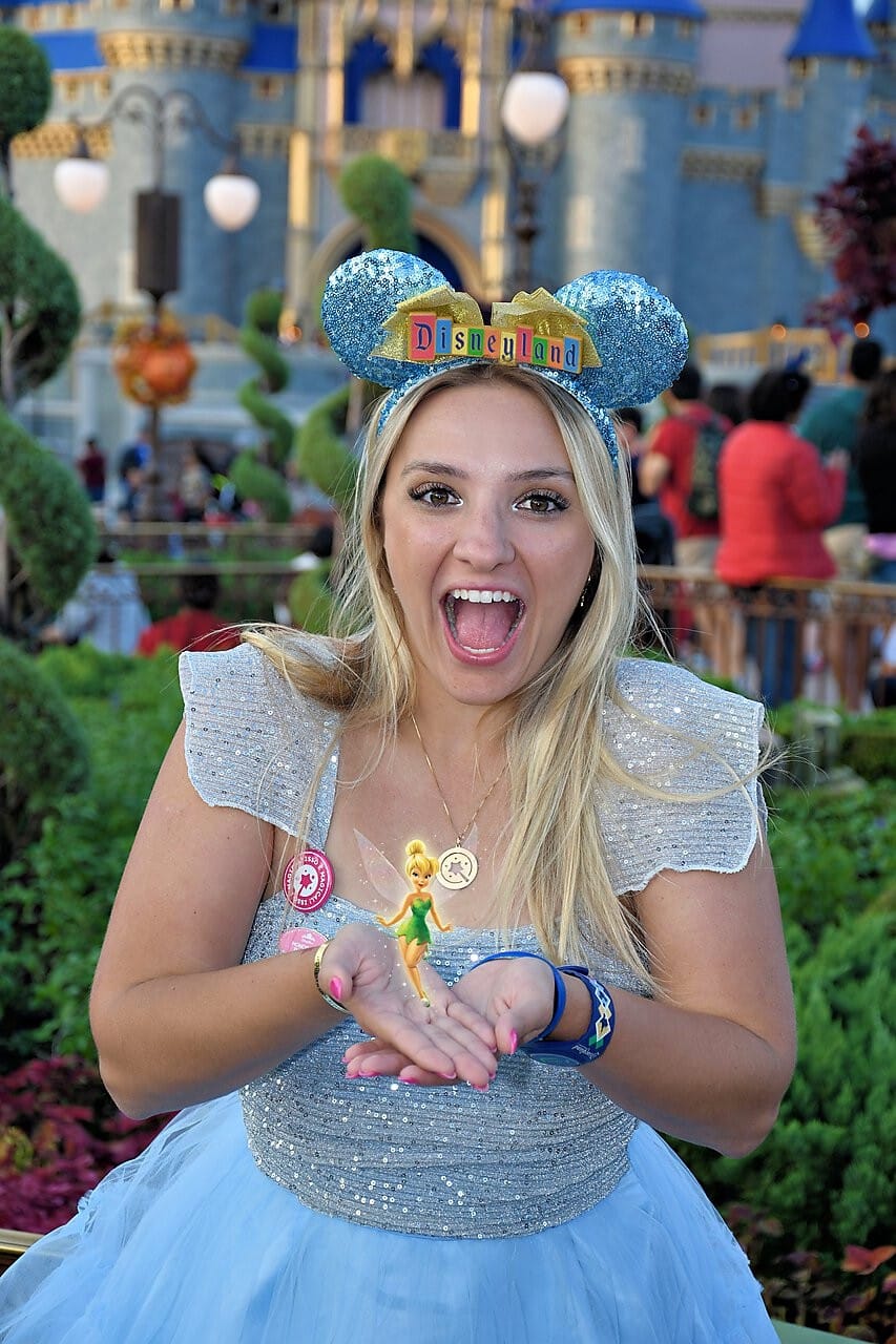 Cliente da Magical Turismo sorrindo em frente ao castelo da Disney, usando orelhas da Disneyland